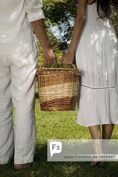 Ein junges Paar hält einen Korb zusammen.