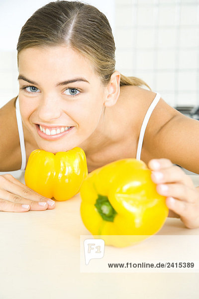 Junge Frau posiert mit gelber Paprika