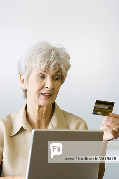 Senior woman making on-line purchase  looking at credit card