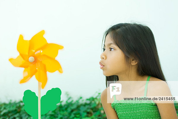 Kleines Mädchen bläst Pinwheel Blume