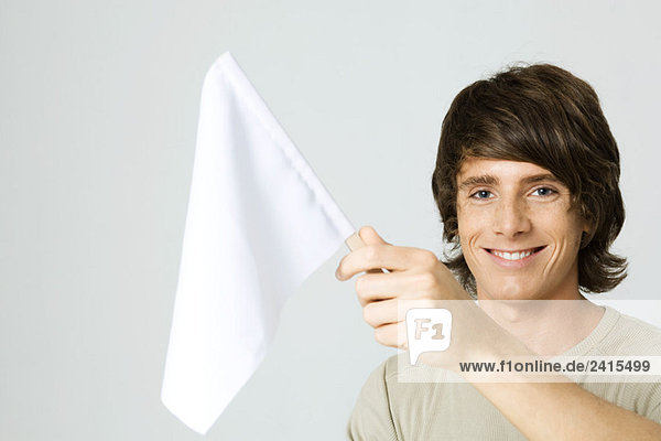 Junger Mann mit weißer Fahne  lächelnd vor der Kamera