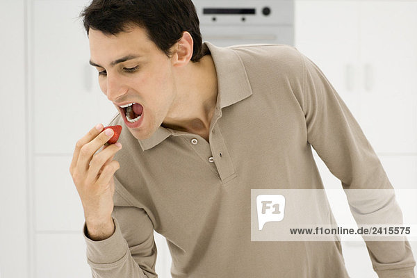 Mann isst Erdbeere  Mund offen