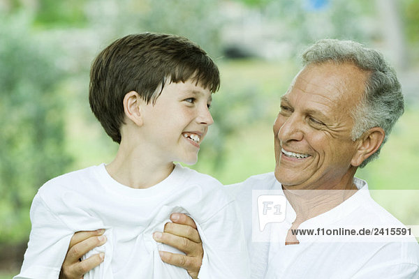 Grandfather and grandson smiling at each other  man holding boy