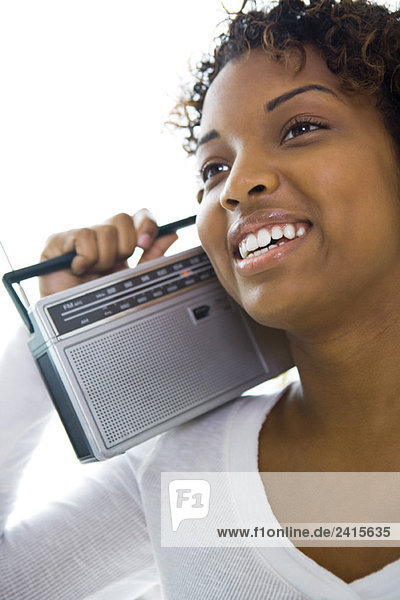 Junge Frau hält Radio auf der Schulter  schaut weg  lächelt
