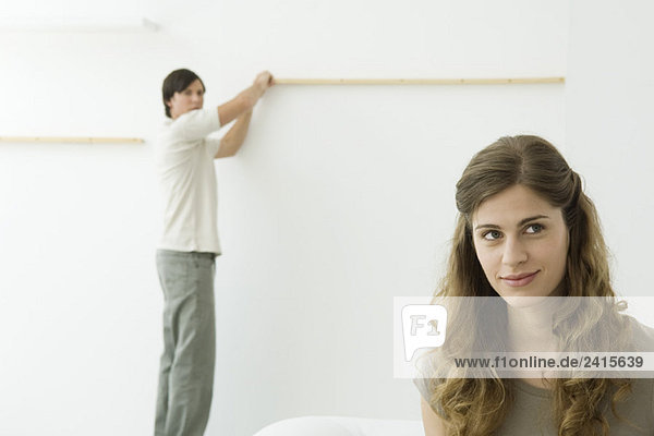 Mann hält Holzpfosten an der Wand  Frau im Vordergrund lächelnd  aufblickend