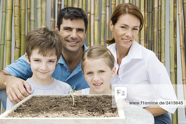 Familie zusammen  lächelnd in die Kamera  Topfpflanze im Vordergrund