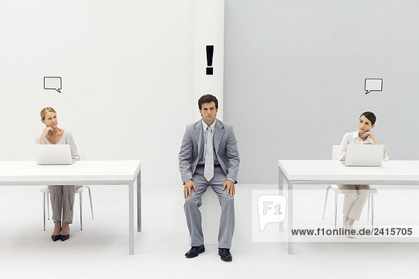 Man sitting in office with exclamation mark over his head  women on either side with blank word bubbles
