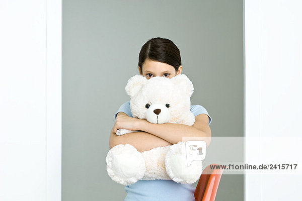Preteen Mädchen umarmen großen Teddybär  Blick in die Kamera