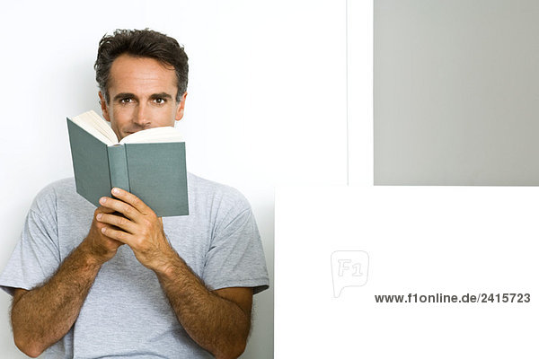 Mann liest Buch  schaut in die Kamera
