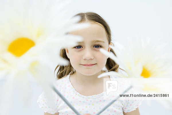 Mädchen hinter Blumen  lächelnd vor der Kamera  Porträt