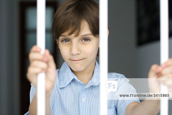 Junge hinter Gittern  lächelnd vor der Kamera