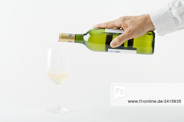 Männerhand gießt Weißwein ins Glas  Ausschnittansicht