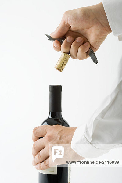 Mann entkorkt Flasche Wein  abgeschnittene Ansicht der Hände