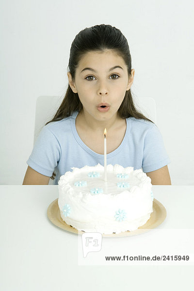 Mädchen bläst Kerze auf Geburtstagskuchen aus  Portrait