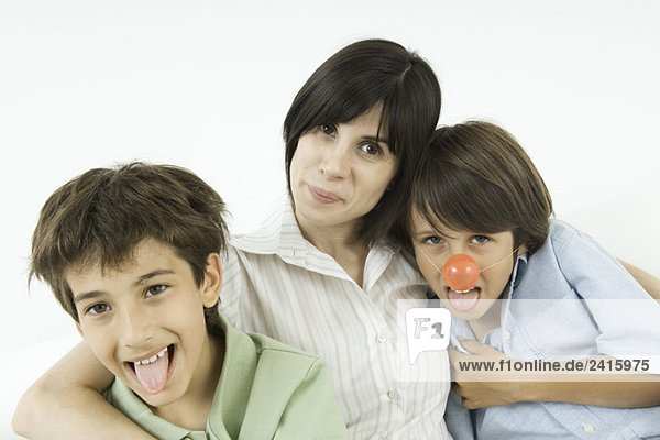 Mother and two sons  boys sticking out their tongues  one wearing clown's nose