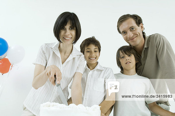 Family with birthday cake  woman holding knife  all smiling