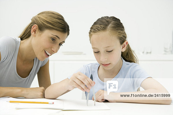 Mädchen bei den Hausaufgaben  mit dem Zeichenkompass  Mutter beim Zuschauen