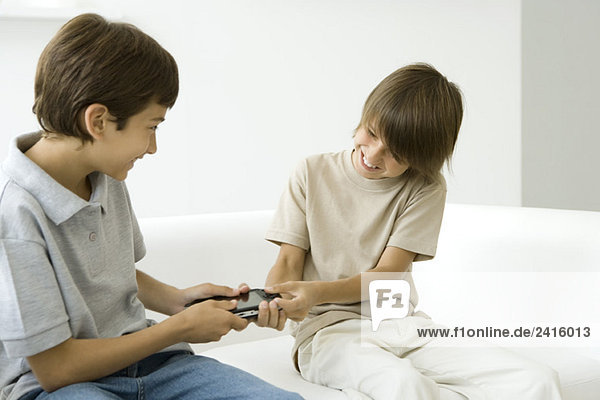 Two brothers fighting over handheld video game