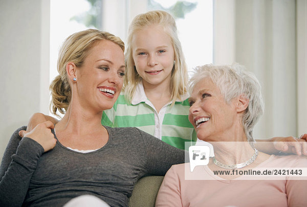 Mädchen (8-9) mit Mutter und Großmutter im Wohnzimmer  lächelnd  Porträt