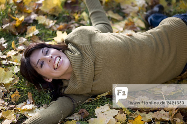Brünette Frau entspannt auf Herbstlaub  Portrait
