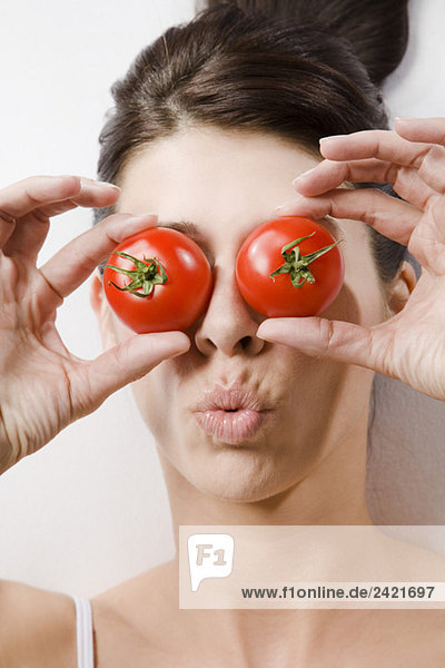 Brünette Frau  die die Augen mit Tomaten bedeckt  Portrait