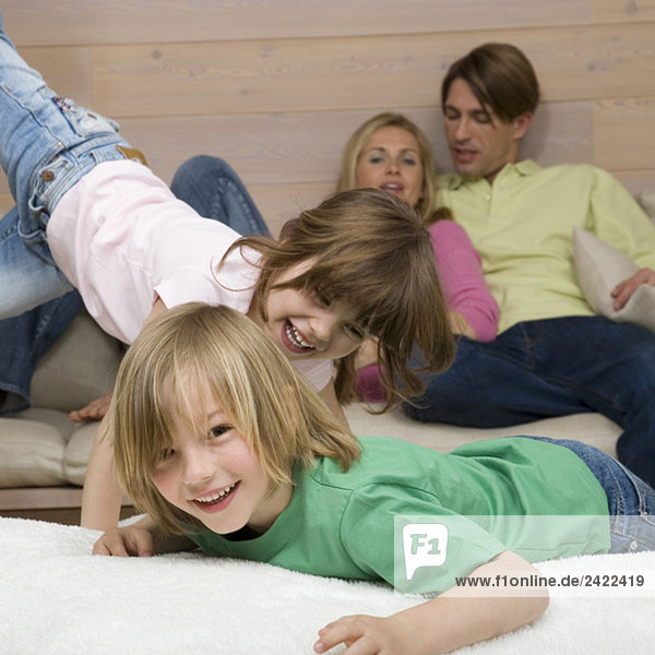 Junge (8-9) und Mädchen (6-7) spielen zusammen  Eltern im Hintergrund  Portrait