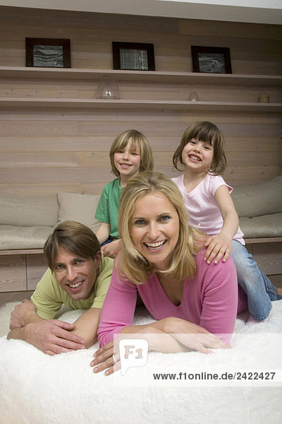 Familie im Wohnzimmer  Kinder sitzen auf dem Hals der Eltern  lächelnd  Porträt