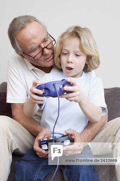 Grandfather and grandson (8-9) playing video game  portrait