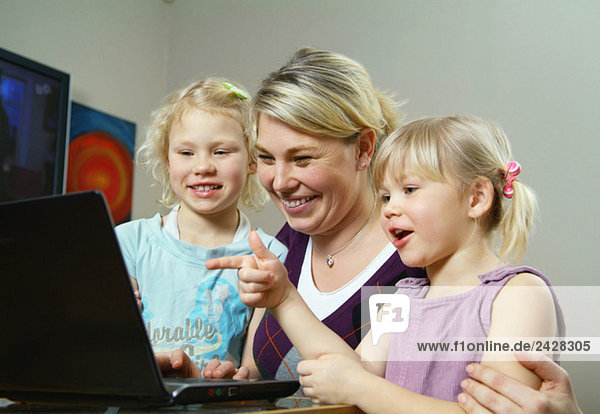 Mother and daughters in front of computer