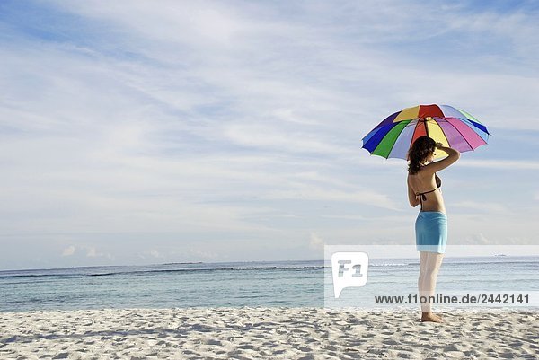 Frau hält Sonnenschirm am Strand
