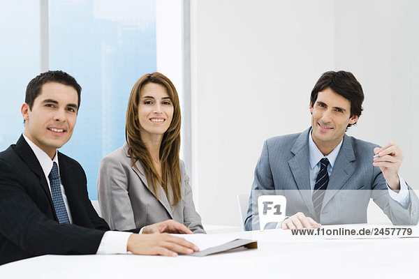 Business colleagues sitting at table  smiling at camera
