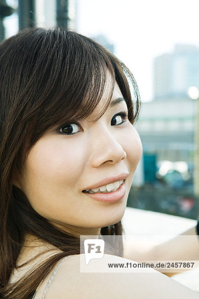 Young woman smiling over shoulder at camera  portrait