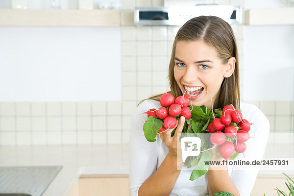 Woman holding up bunches of fresh radishes  smiling at camera