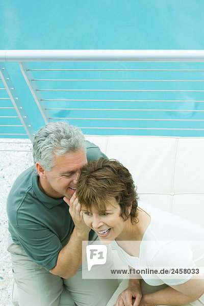 Couple sitting on balcony  man whispering in woman's ear  high angle view