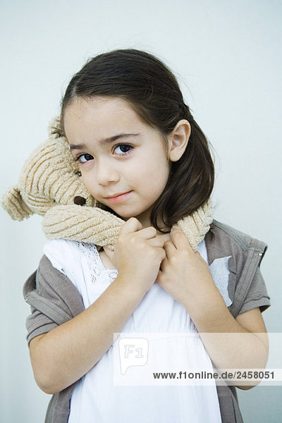 Kleines Mädchen mit Teddybär um den Hals  lächelnd vor der Kamera  Porträt