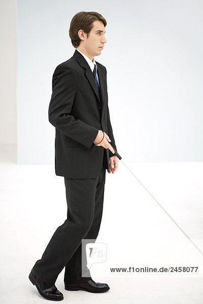 Businessman walking with white cane  side view