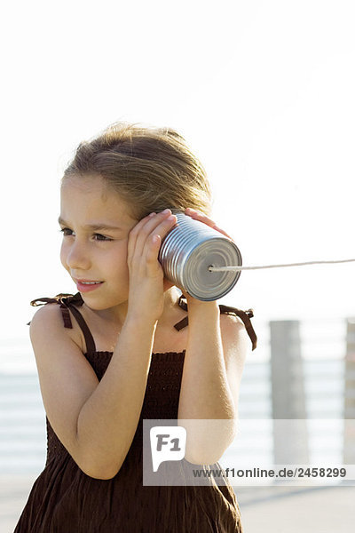 Kleines Mädchen hört Blechdosentelefon