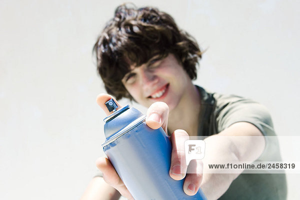Teenager-Junge zeigt Dose Sprühfarbe auf die Kamera  Fokus auf den Vordergrund