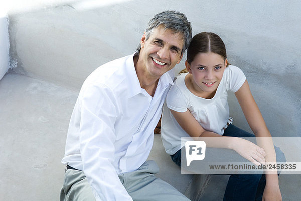 Vater und Tochter sitzen zusammen  lächeln vor der Kamera  Porträt