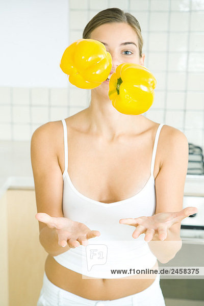Frau jongliert mit gelben Paprika in der Küche