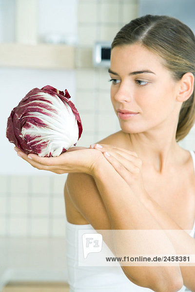 Frau die einen Kopf aus Radicchio-Salat betrachtet und hält. Frau, die einen Kopf aus Radicchio-Salat betrachtet und hält.