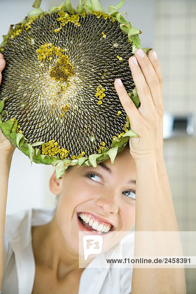 Frau hält großen getrockneten Blütenkopf hoch  schaut nach oben  lächelt
