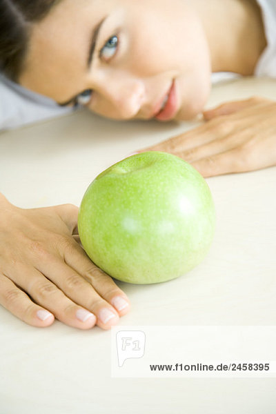 Frau ruht Kopf auf dem Tresen hinter dem Apfel  Blick nach oben  Fokus auf den Vordergrund
