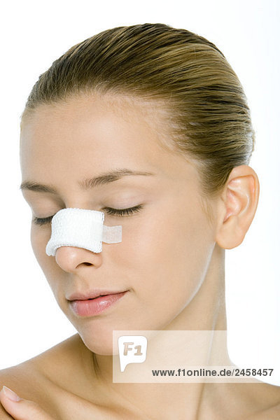 Young woman with bandaged nose  eyes closed