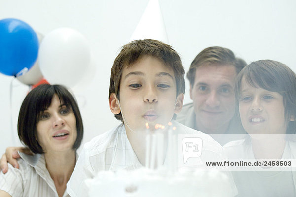 Junge bläst Kerzen auf Geburtstagskuchen aus  Familie beobachtet  Mund