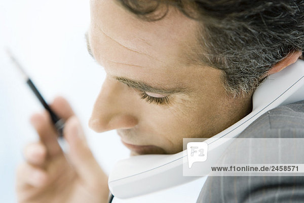 Mann hält Telefon zwischen Kinn und Schulter  Seitenansicht  Nahaufnahme