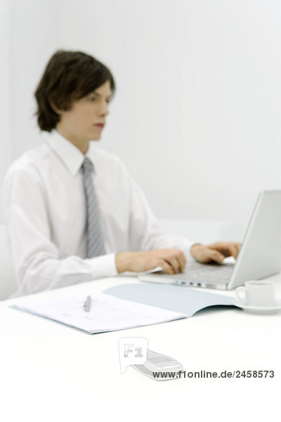 Young professional working at desk  focus on cell phone in foreground