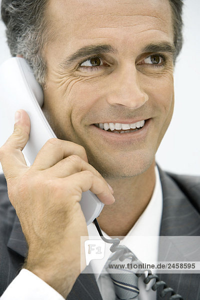 Man using landline phone  smiling  looking away