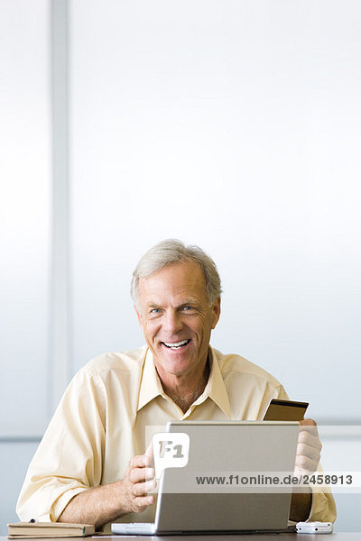 Man making on-line purchase with credit card  smiling at camera