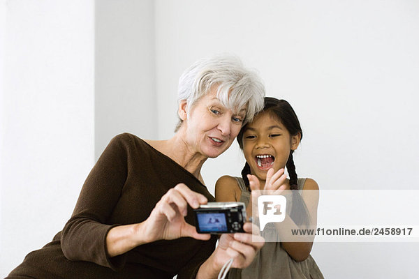 Seniorin fotografiert sich selbst und Enkelin mit Digitalkamera  beide lachend